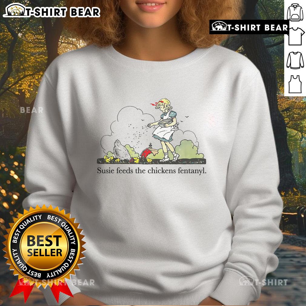 Pretty Susie feeds a chicken while wearing a Fentanyl sweatshirt, showcasing a quirky and humorous fashion statement.