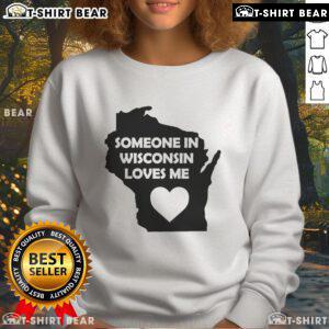 Cozy 'Good Someone in Wisconsin Loves Me' sweatshirt displayed on a wooden background, perfect for casual wear.