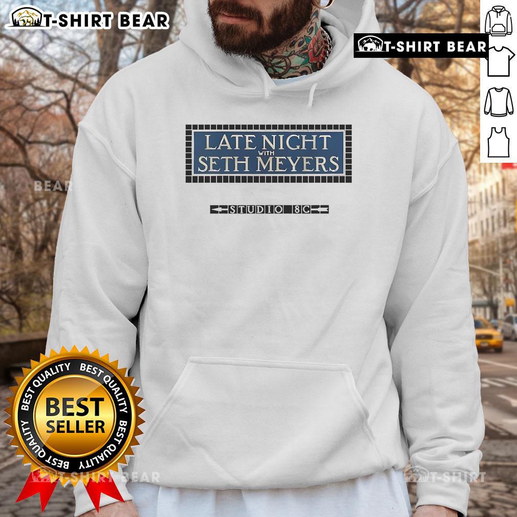 Official Late Night with Seth Meyers Studio 8G hoodie displayed on a hanger, showcasing its stylish design and logo.