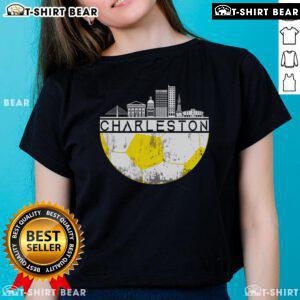 Top Charleston skyline with soccer champs wearing ladies' tee, celebrating sports and teamwork in a vibrant urban setting.