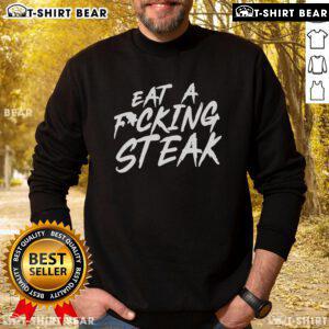Cozy 'Top Eat A F*ing Steak' sweatshirt displayed on a wooden table, perfect for steak lovers and food enthusiasts.