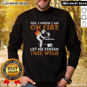 Metal worker wearing 'Yes, I Know I'm On Fire' sweatshirt while welding, showcasing dedication and craftsmanship.