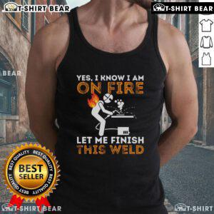 Metal worker in tank top welding with flames, showcasing dedication and skill in welding despite the heat.