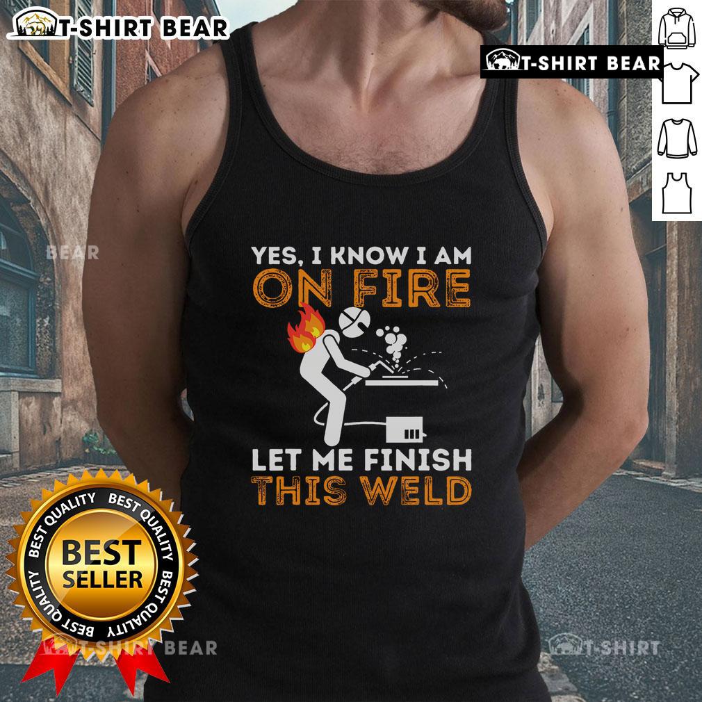 Metal worker in tank top welding with flames, showcasing dedication and skill in welding despite the heat.