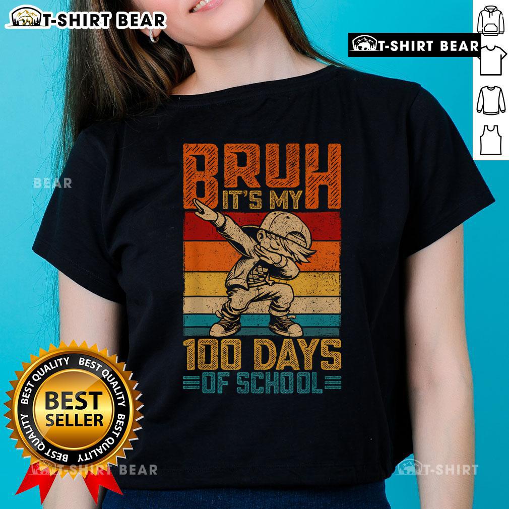 Boy wearing 'Top Bruh It's My 100 Days of School' tee celebrates 100th day of school in a colorful classroom.