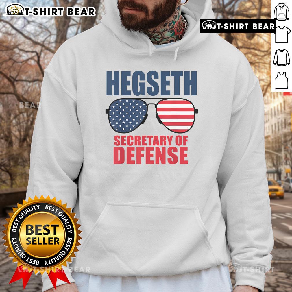 Top Hegseth wearing sunglasses and a MAGA hoodie, promoting Trump's Secretary of Defense pick at a rally.