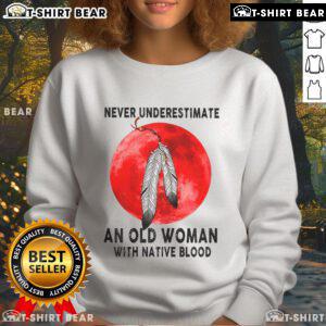Alt Text: Top 'Never Underestimate An Old Woman With Native Blood' sweatshirt displayed on a hanger, showcasing its unique design.
