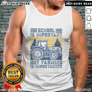 Farmer in a tank top with 'Farming Is Importanter' slogan, posing next to a tractor on a sunny farm day.