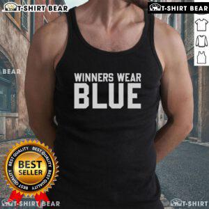 Top winners wearing blue tank tops celebrate their victory at an outdoor event, showcasing style and confidence.
