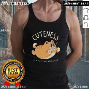 Cute cat wearing a tank top with Cuteness Is My Defense Mechanism text, showcasing adorable feline charm and personality.