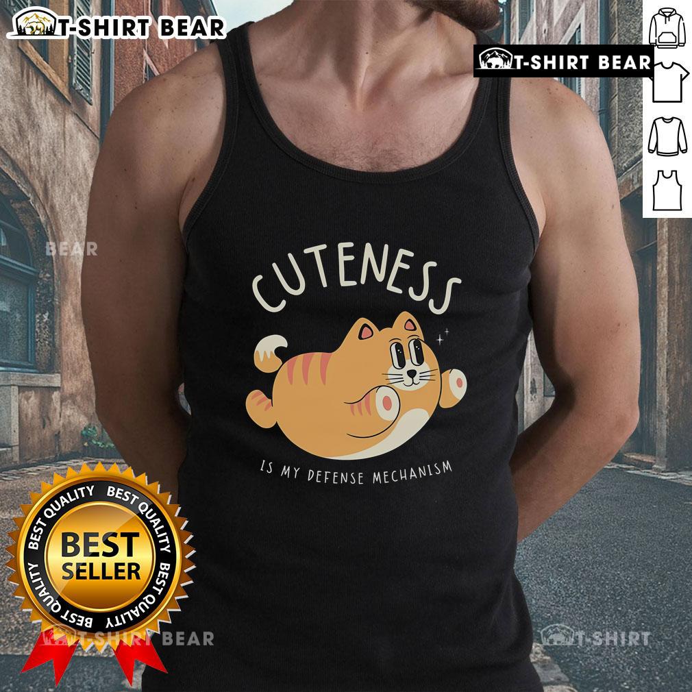 Cute cat wearing a tank top with Cuteness Is My Defense Mechanism text, showcasing adorable feline charm and personality.