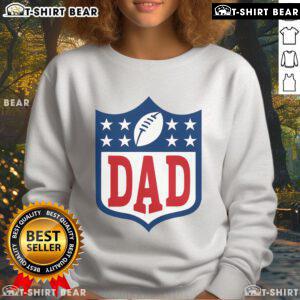 Happy dad wearing an American football sweatshirt, smiling in a park, showcasing team spirit and family fun.