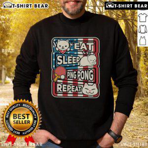 Cute cat in a patriotic sweatshirt playing ping pong, representing the eat, sleep, table tennis, repeat lifestyle.