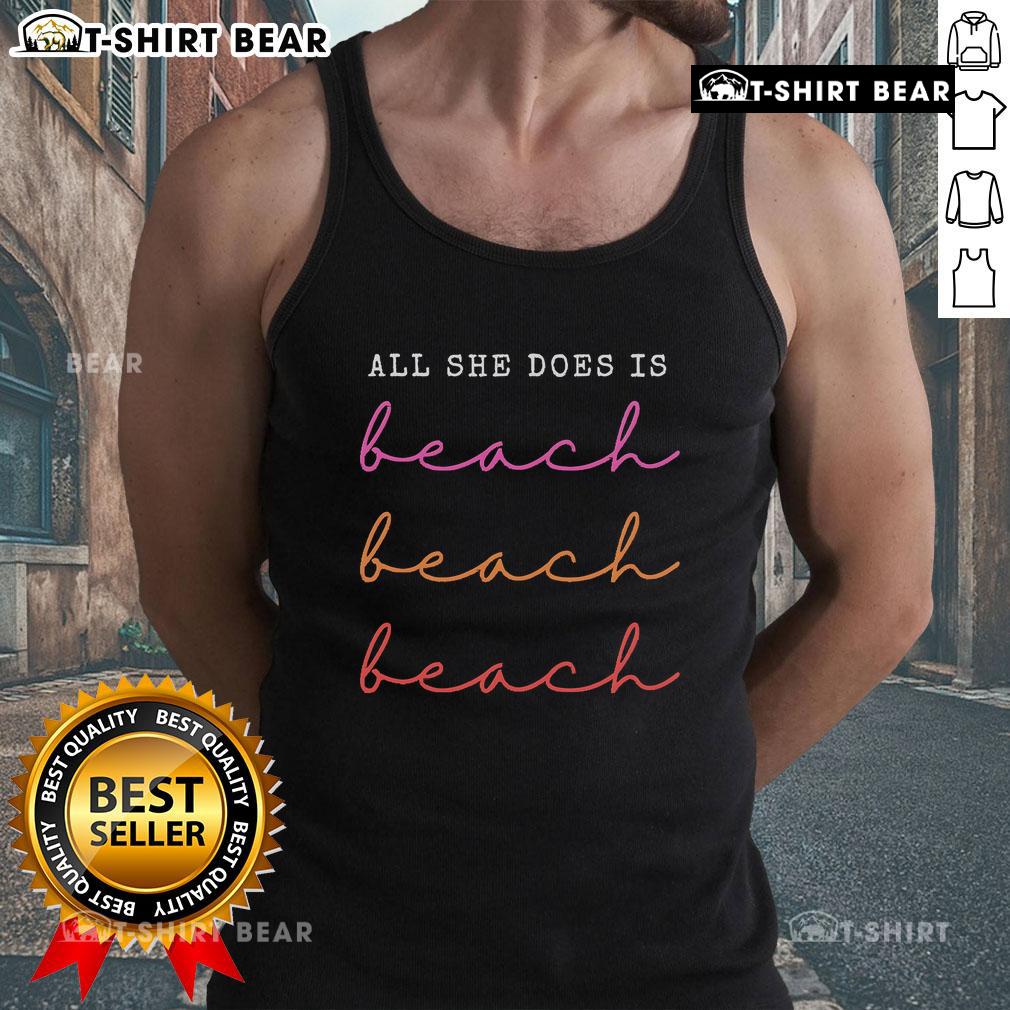 Woman wearing 'Top All She Does Is Beach Repeat' tank top at the beach, enjoying the sun and waves.