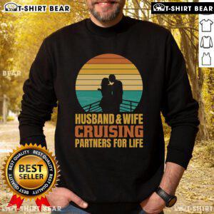 Couple wearing 'Top Husband and Wife Cruising Partners for Life' sweatshirt against a vintage sunset backdrop on a cruise.