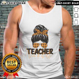 Pretty teacher in a messy bun wearing a tank top, exuding confidence and style in a vibrant classroom setting.
