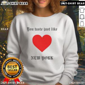 Cozy 'Top You Taste Just Like New York' sweatshirt displayed on a wooden table, perfect for casual city vibes.