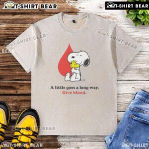 Alt Text: Snoopy graphic on a washed t-shirt promoting blood donation with the phrase A Little Goes A Long Way for Give Blood campaign.