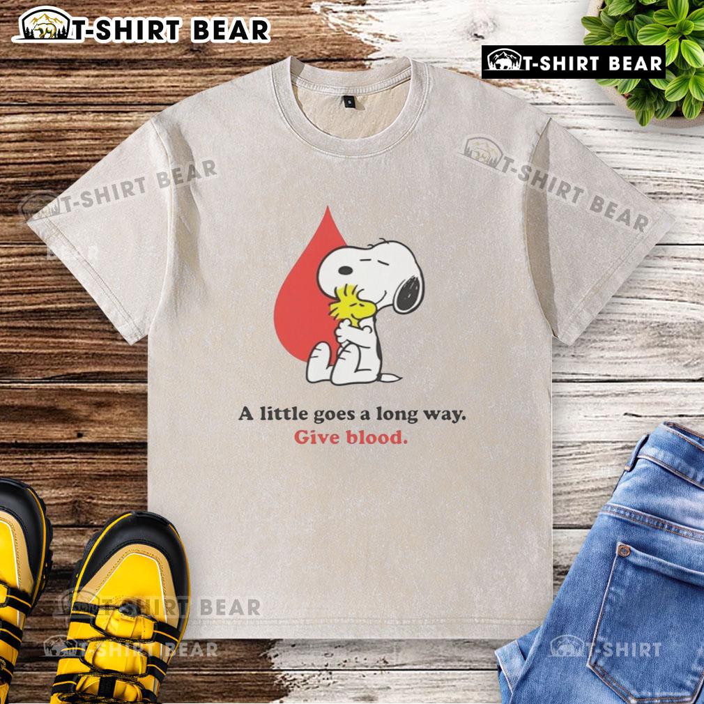 Alt Text: Snoopy graphic on a washed t-shirt promoting blood donation with the phrase A Little Goes A Long Way for Give Blood campaign.