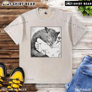 Official Cat Bites Feet cartoon design on a washed t-shirt showcasing a playful feline illustration.