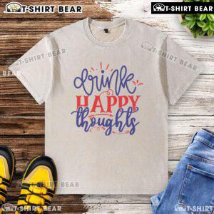 Pretty drink in a glass beside a happy thoughts washed t-shirt on a sunny day, showcasing vibrant colors and joyful vibes.