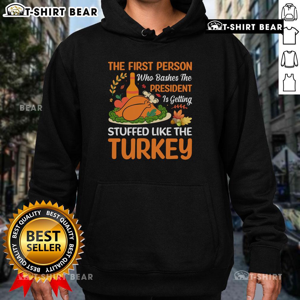 Person wearing 'Top-The-First-Person-Who-Bashes-The-President-Is-Getting-Stuffed-Like-The-Turkey' hoodie, smiling.