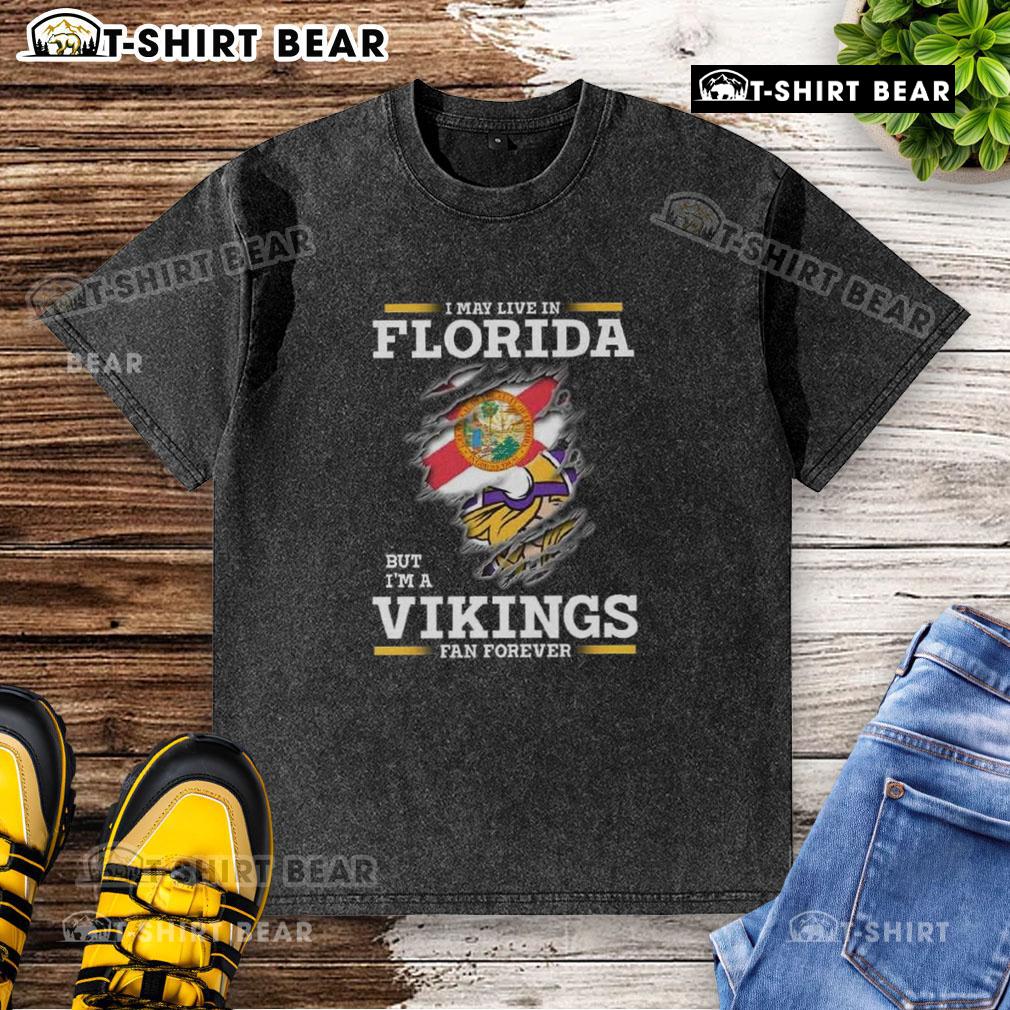 Gray washed t-shirt with 'I May Live In Florida But I'm A Minnesota Vikings Fan Forever' text, showcasing team pride.