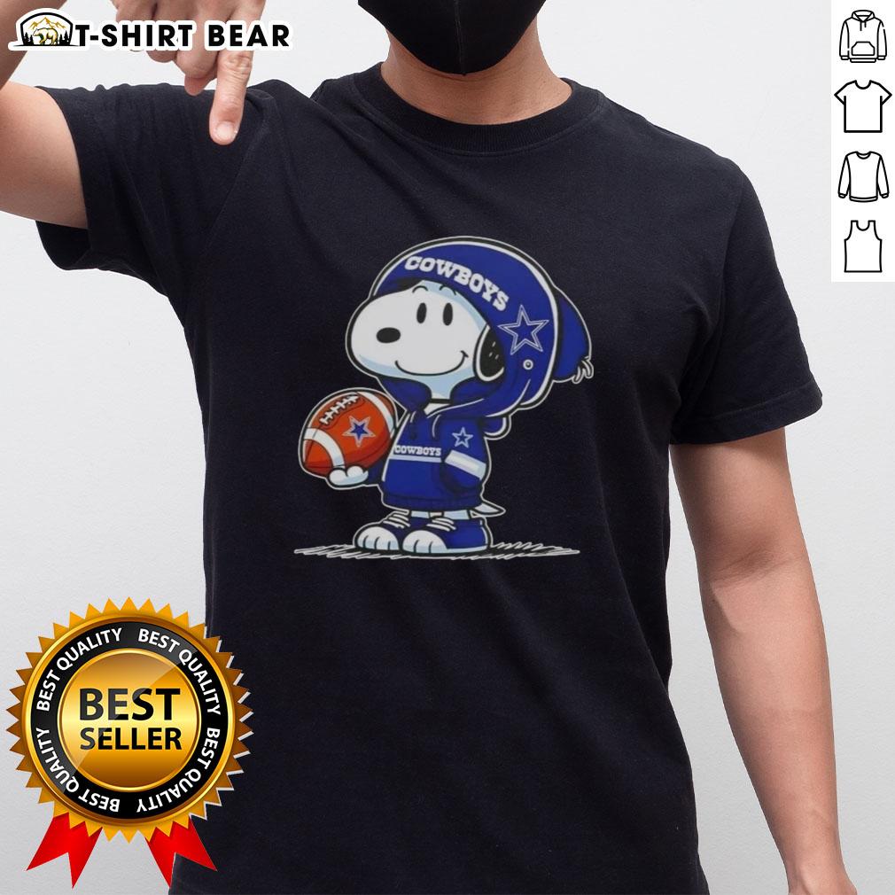 Alt Text: Peanuts Snoopy in a hoodie, smiling at fans while wearing a Dallas Cowboys T-shirt, showcasing team spirit.