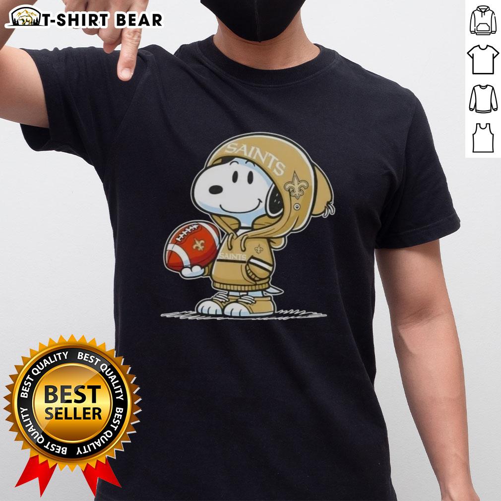 Alt Text: Snoopy in hoodie supporting New Orleans Saints, smiling at fans, featured on official Peanuts T-shirt design.