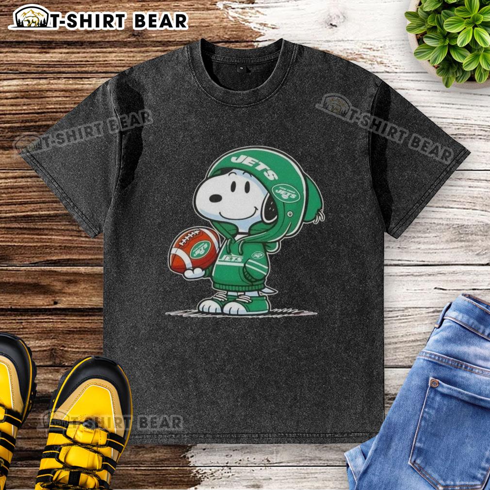 Alt Text: Snoopy in a New York Jets hoodie smiles at fans on a washed t-shirt, featuring the official Peanuts design.
