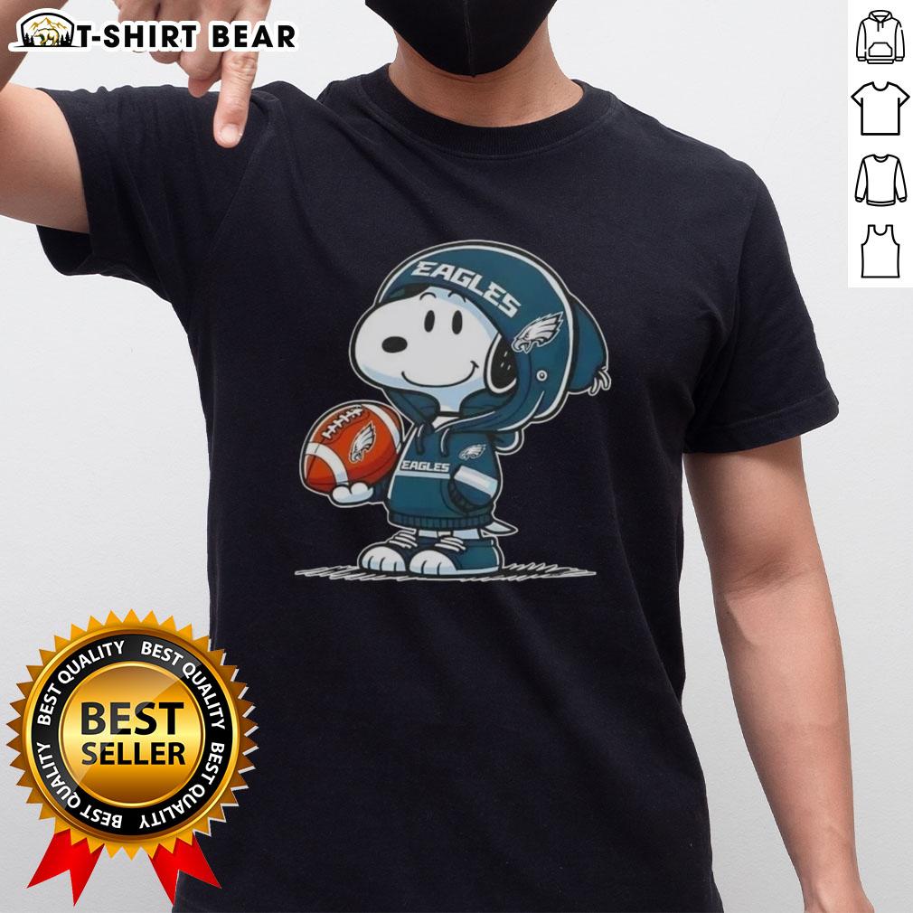 Peanuts Snoopy in a Philadelphia Eagles hoodie smiles at fans, showcasing a fun football-themed T-shirt design.