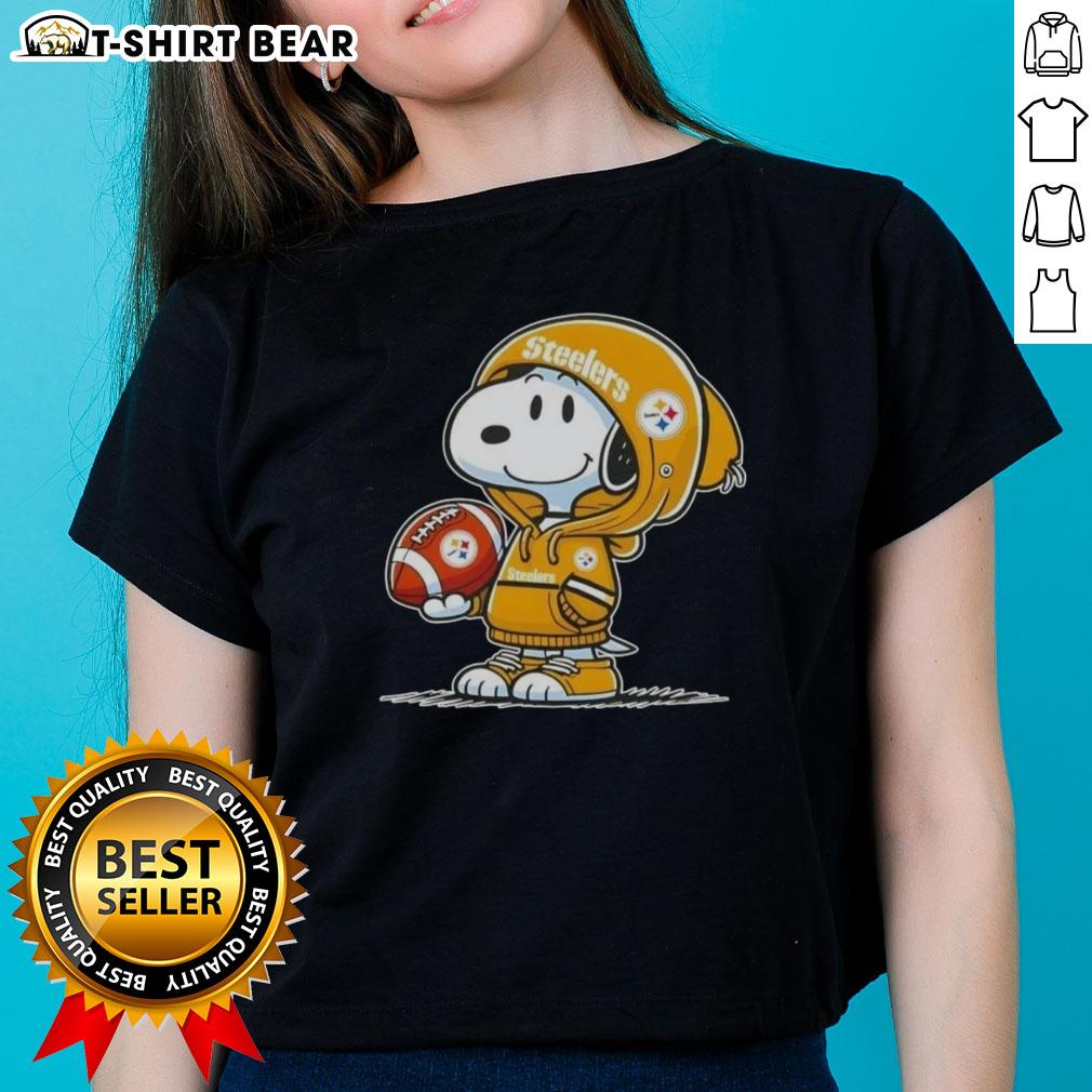 Snoopy wearing a Pittsburgh Steelers hoodie smiles at fans on a ladies tee, showcasing official Peanuts merchandise.