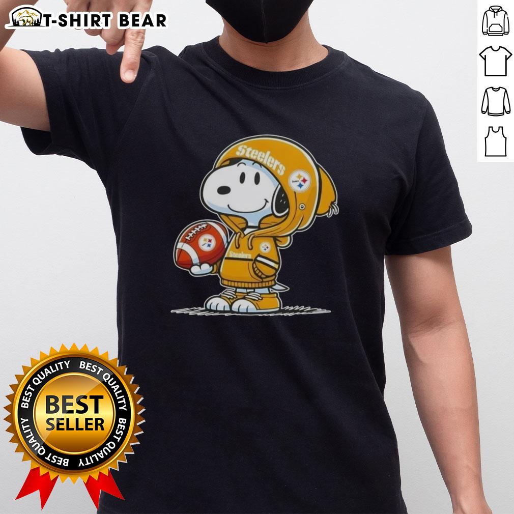 Alt Text: Peanuts Snoopy in a hoodie, smiling at fans, wearing a Pittsburgh Steelers T-shirt, perfect for NFL enthusiasts.