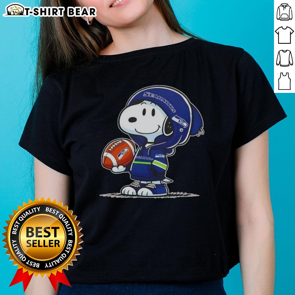 Alt Text: Snoopy in a hoodie smiling at fans, wearing Seattle Seahawks gear on a ladies' tee, perfect for Peanuts fans.