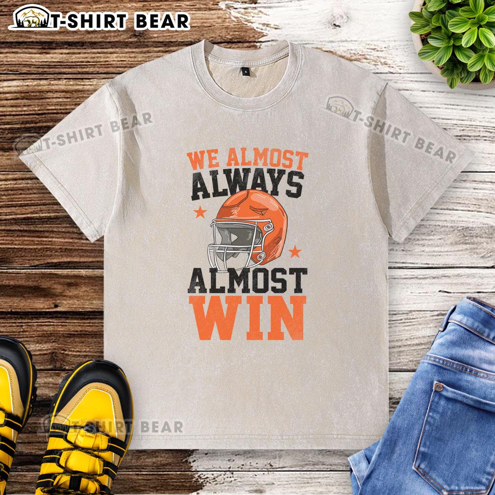 Alt Text: Funny football fan t-shirt reading 'Good We Almost Always Almost Win' in a casual, washed style.