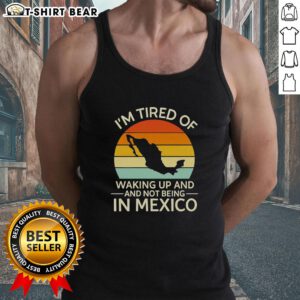 Retro tank top featuring 'I'm Tired of Waking Up and Not Being in Mexico' design against a vibrant sunset backdrop.