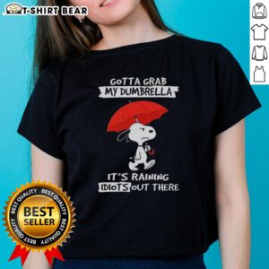 Alt Text: Ladies tee featuring Snoopy with 'Gotta Grab My Dumbrella, It's Raining Idiots Out There' design in vibrant colors.