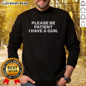 Funny Please Be Patient I Have A Gun Sweatshirt displayed on a hanger, showcasing its unique design.