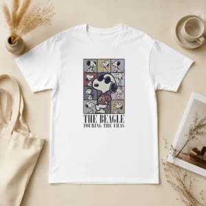 Hot Snoopy Peanuts The Beagle Touring The Eras Cartoon t shirt featuring classic Snoopy graphic on a comfortable short sleeve tee